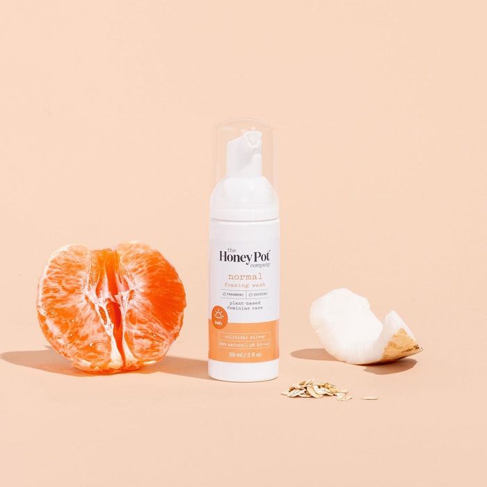 Half an orange next to the bottle, with a slice of fruit and grains