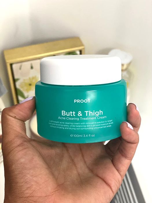 Model holding a green container of Butt & Thigh acne treatment cream