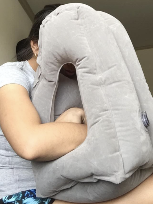 A reviewer with their head resting on an inflated pillow placed on their lap, with enough space for their arms.