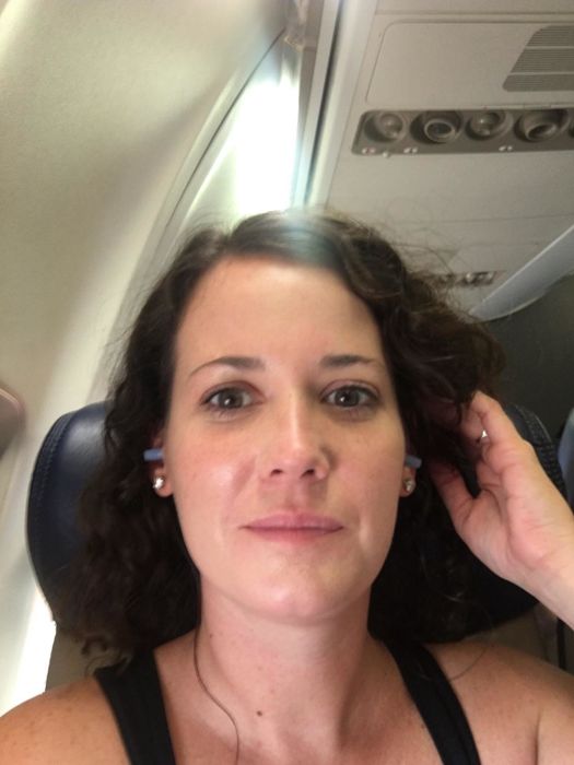A reviewer photo on an airplane, wearing the earplugs.