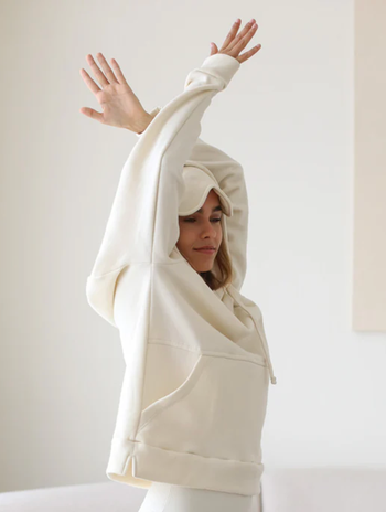 A person stretches while wearing an oversized, cozy hoodie, ideal for a laid-back, casual look.