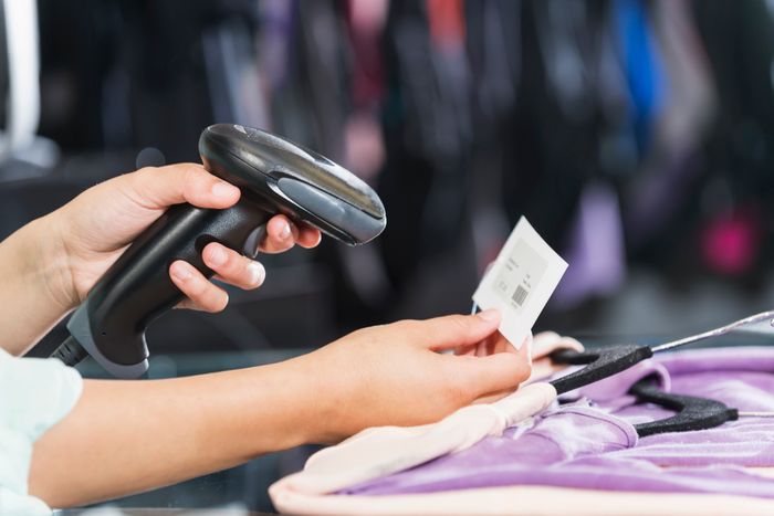 A shopper scanning a barcode on an item of clothing at the checkout counter in a store.