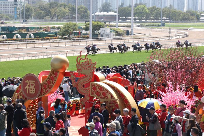 A bustling outdoor horse race event with lively crowds, festive decorations, and blossoming trees, capturing the vibrant atmosphere of the occasion.
