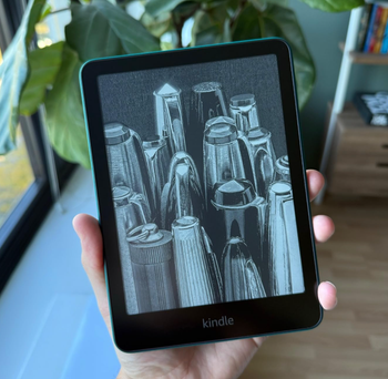 A person holding a Kindle with a sketch of various pen tips on the screen, surrounded by a cozy background of plants and a bookshelf, ideal for reading