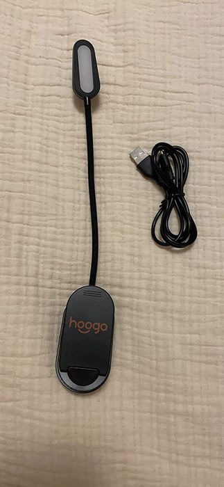 An amber clip-on light displayed with its charger.