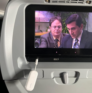The small white device plugged into a plane screen via USB.