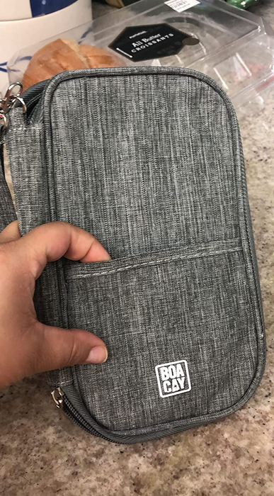 A reviewer holds a gray-colored travel document holder.