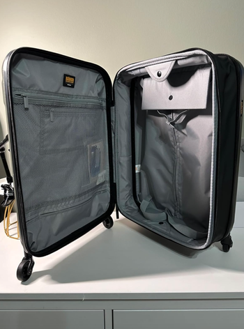 An open suitcase with organized compartments and four wheels, displayed in a well-lit setting, ideal for a shopping article about travel essentials.