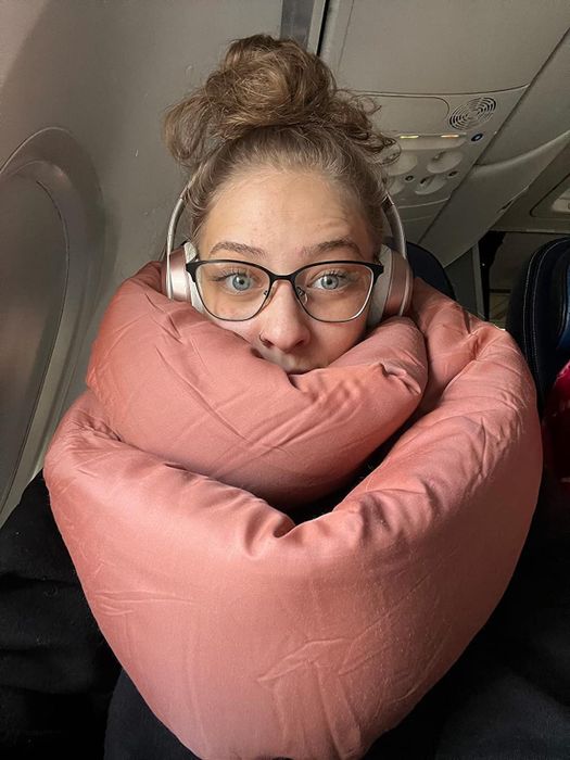 A reviewer wearing a terracotta-colored scarf-like infinity pillow around their neck.