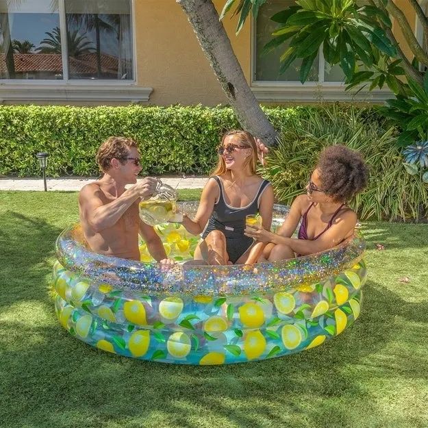 Three adults enjoying themselves in the inflatable pool.