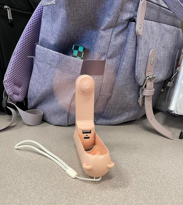 A reviewer showing the pink mini fan switched on and ready to go.