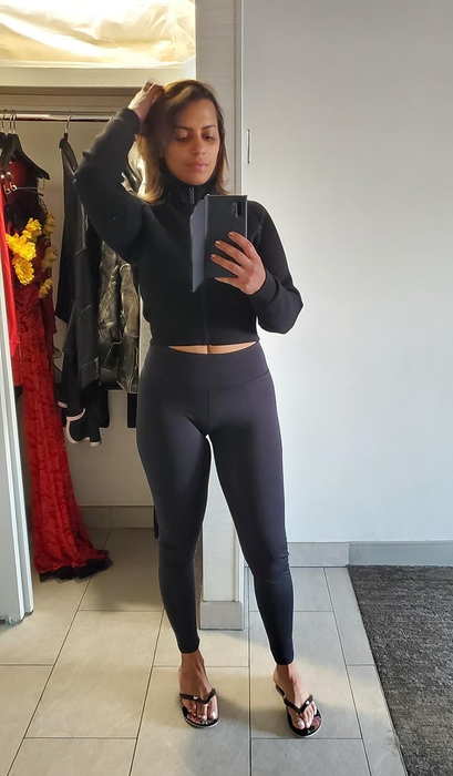A reviewer demonstrating how the black leggings fit on them from the front.