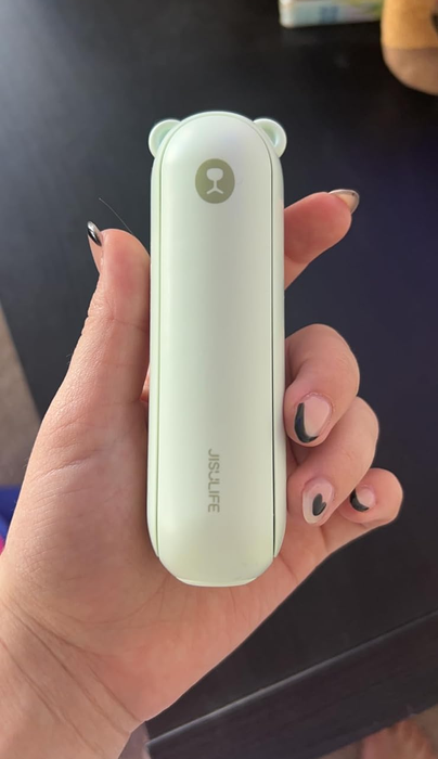 A reviewer holding up the green mini fan for display.