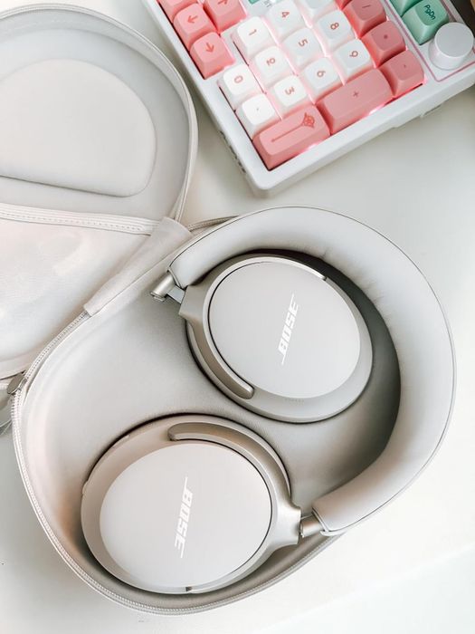 A pair of white Bose headphones neatly folded into their protective case.