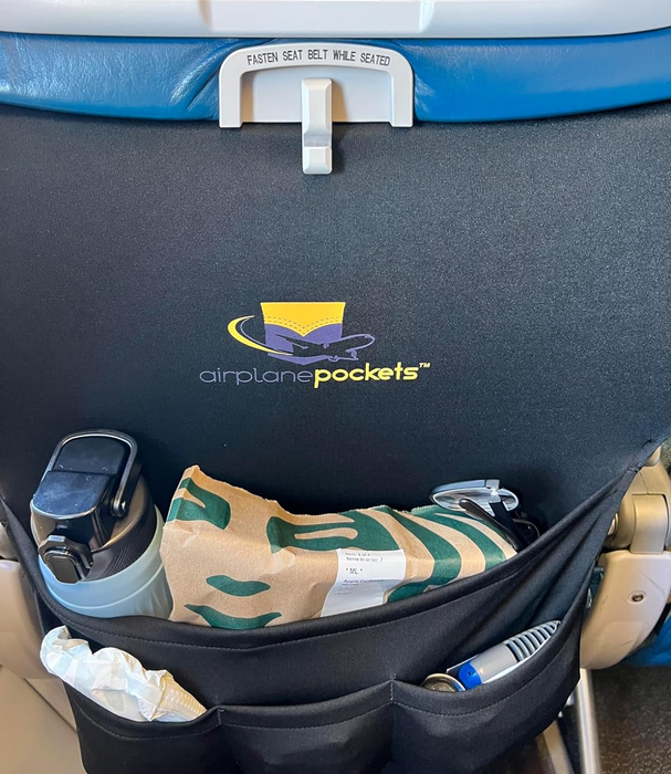 A reviewer showing off their Starbucks snack, water bottle, and other personal items tucked into the tray table cover.