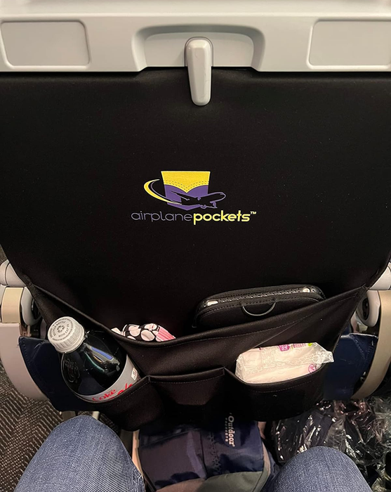 A reviewer with their soda bottle, baby wipes, and other personal belongings neatly arranged in the tray table cover.