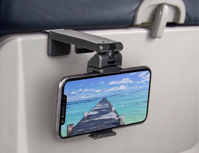 A phone mounted on the back of an airplane tray table.