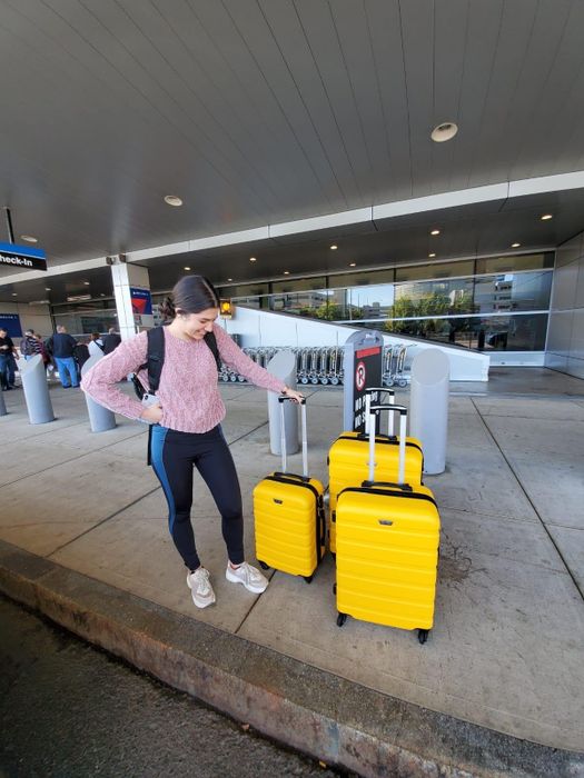 A photo of a reviewer with the three-piece luggage set in a bright yellow color.