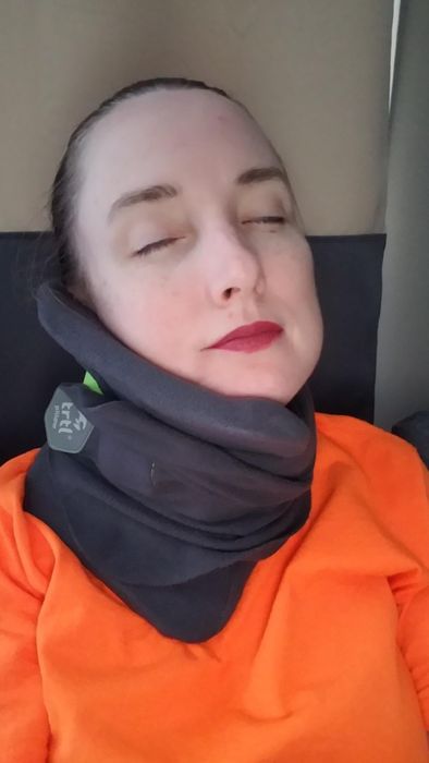 A reviewer sporting a black Trtl neck pillow during their flight.