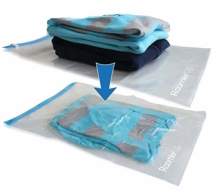 A comparison image showing one space-saver bag with clothes on top, and another bag filled with clothes, illustrating how much smaller the packed clothes become.