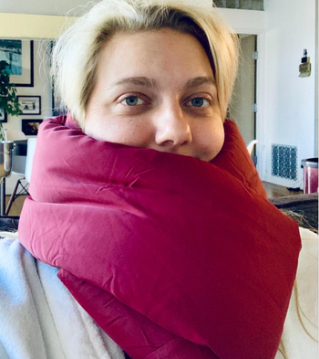 A reviewer wearing a magenta scarf-like pillow around their neck.