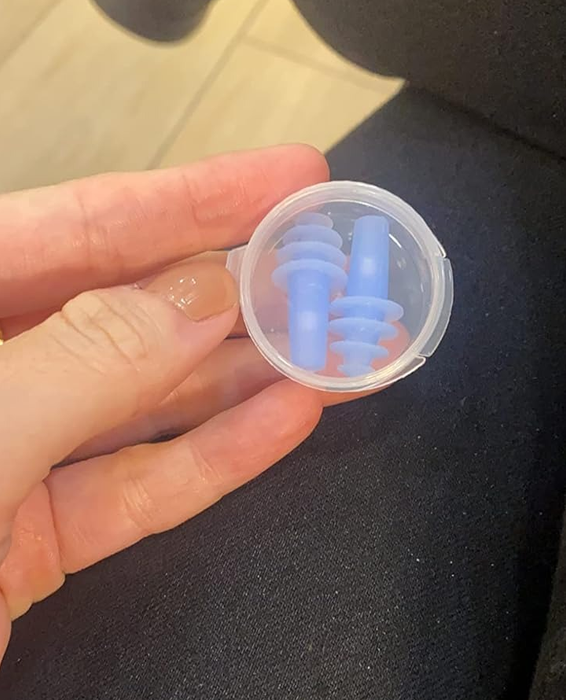 A reviewer holding the transparent container with a pair of Earplanes inside.
