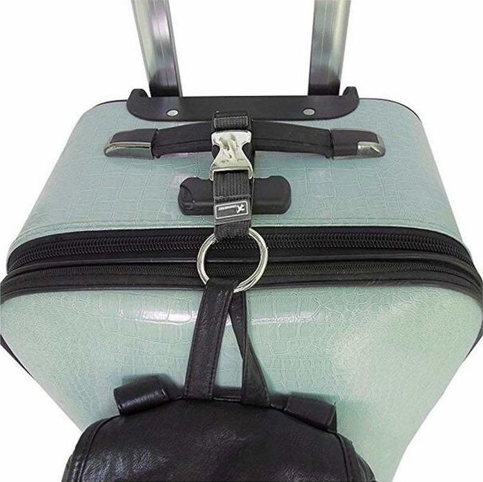 The black strap securing a backpack to a suitcase.