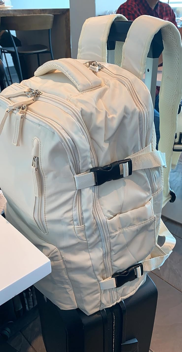 A reviewer’s beige backpack resting on top of their suitcase.