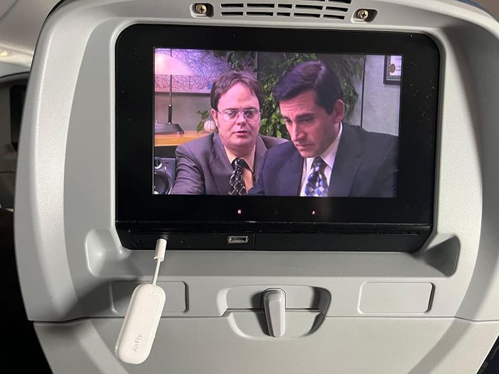 The reviewer's transmitter plugged into their plane’s entertainment system while they enjoy a TV show.