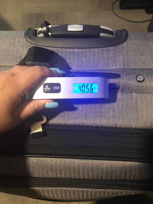 A reviewer holding the scale, showcasing the weight of their luggage.