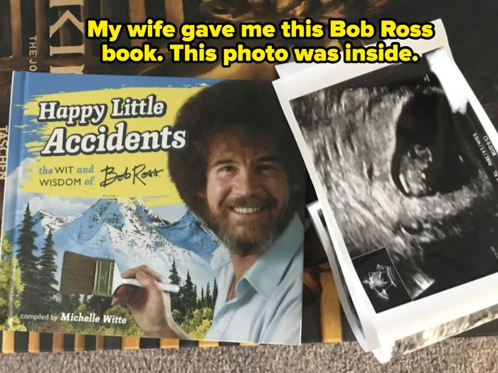 A book titled 'Happy Little Accidents' by Bob Ross placed next to a sonogram image on a table