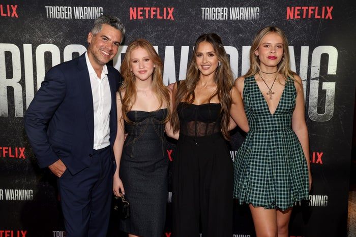 Cash and Jessica grace the red carpet at a Netflix event, dressed in tailored suits, fitted dresses, and plaid patterns.