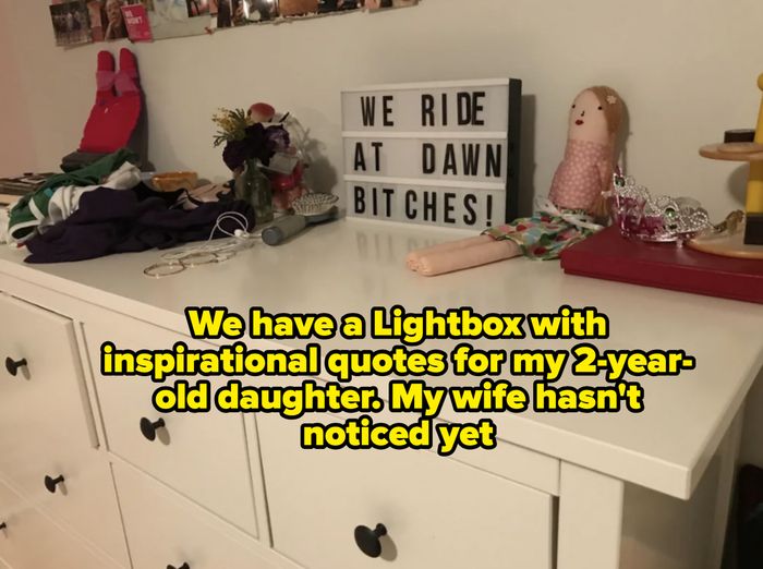A room dresser cluttered with various objects and a lightbox sign boldly proclaiming