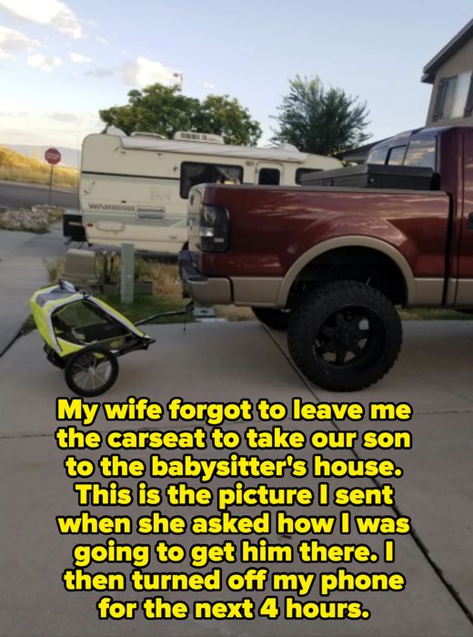 A truck with a raised suspension parked in a driveway, towing a small bike trailer, with an RV in the background