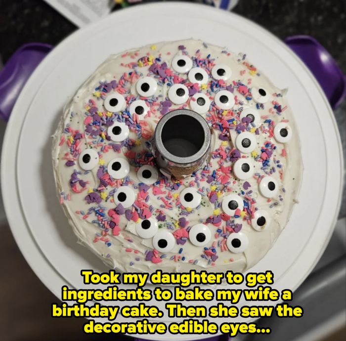 A fun and whimsical cake topped with frosting, bright sprinkles, and playful edible candy eyes, sitting on a white round platter