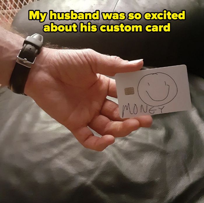 A hand is holding a mock credit card with a smiley face and the word