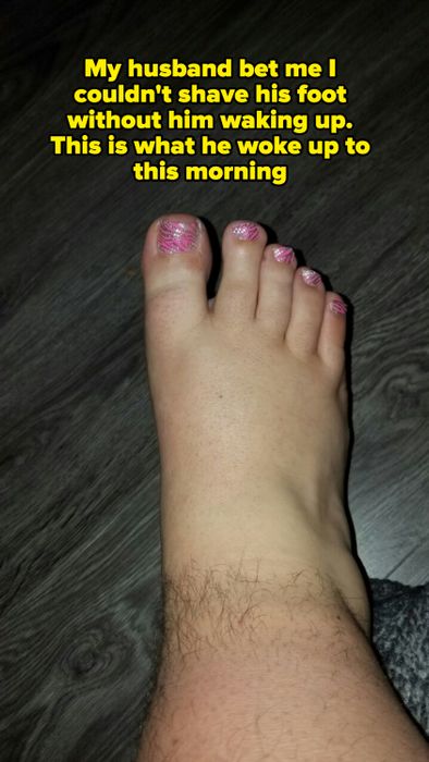 A close-up shot of a foot with pink glitter nail polish on the toes, placed on a dark, textured floor.