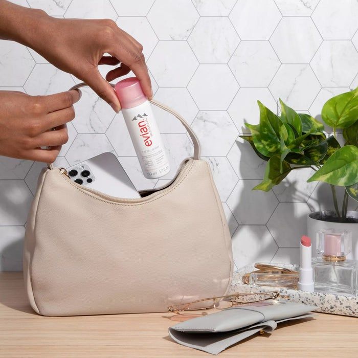 A model showing the spray being placed into a handbag