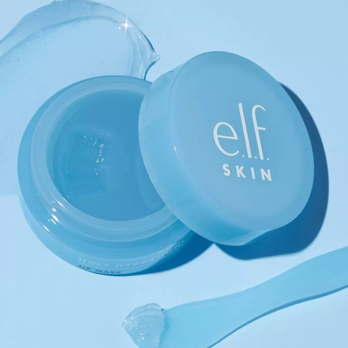 A jar of e.l.f. SKIN Holy Hydration Face Cream with a small spatula and a dollop of cream spread across a light-colored surface.