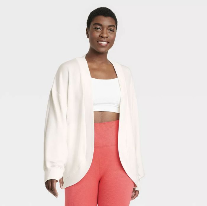 Person wearing a white open-front cardigan, white crop top, and high-waisted textured pants