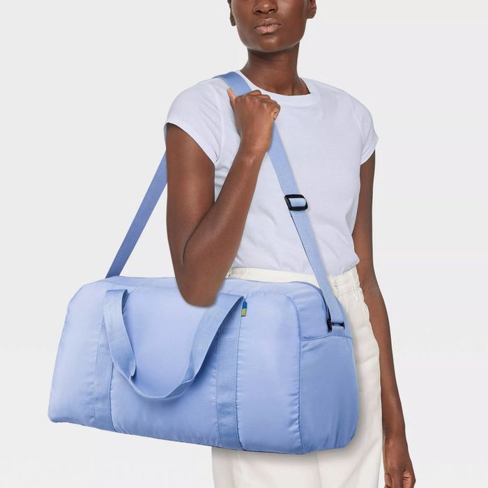 A model showcasing the periwinkle duffle bag, fully packed