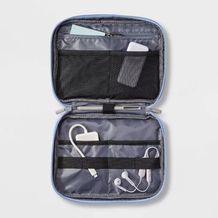 Open tech accessory organizer displaying pockets filled with cables and earphones