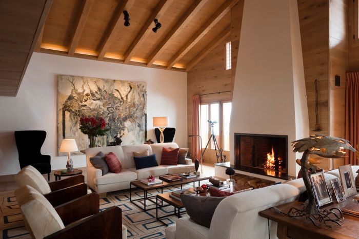 A warm and inviting living room featuring a glowing fireplace, plush sofas, and rustic wooden ceiling beams.