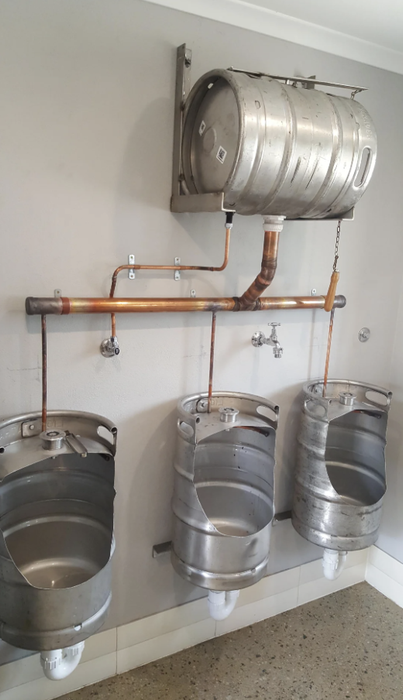 A uniquely designed bathroom featuring beer kegs transformed into urinals