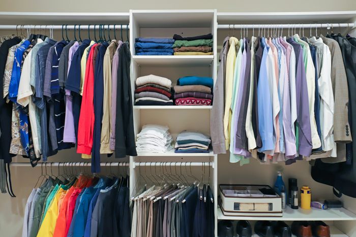 A well-organized closet with neatly arranged clothes and shelves stacked with folded items