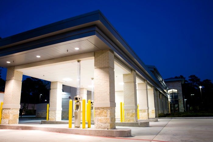 Drive-thru banking area with multiple ATMs under a well-lit canopy at dusk
