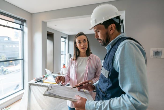 Woman discussing repair details with a contractor inside her home
