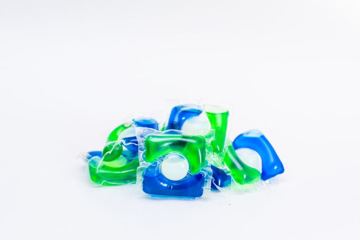 A pile of mixed laundry detergent pods set against a simple background