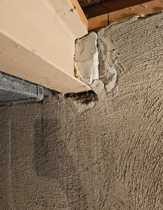 Close-up of a damaged wall corner showing visible signs of wear and patchy repairs.