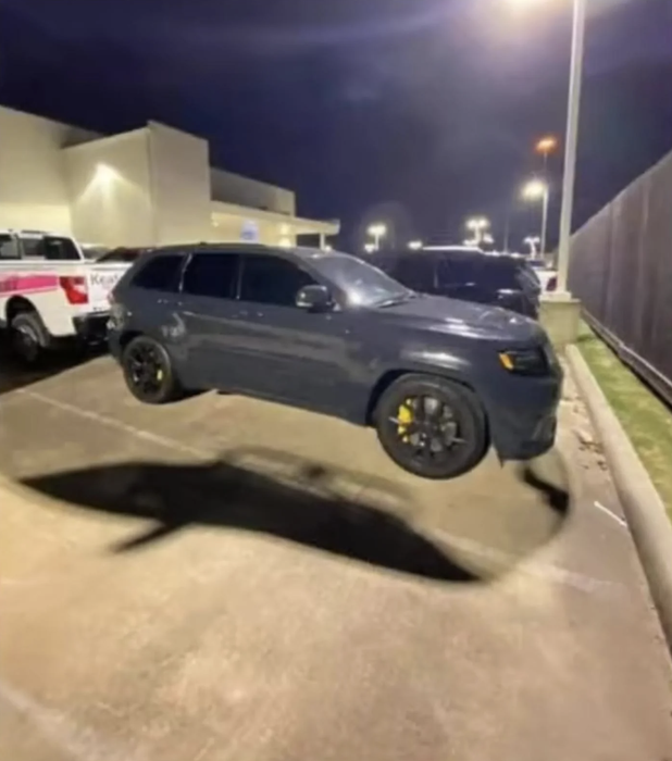 A car parked in a lot at night seems to hover slightly above the ground.